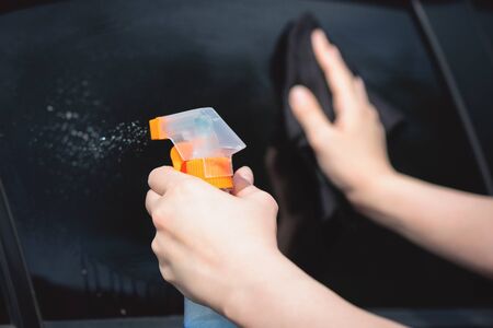 Cleaner is cleaning a car window glass with a rag and detergent close up.の写真素材