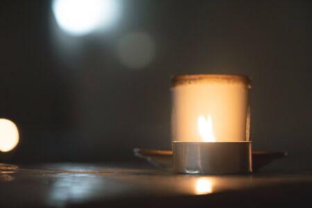 Blurred tea cup with a burning candle on the foreground close up.の写真素材