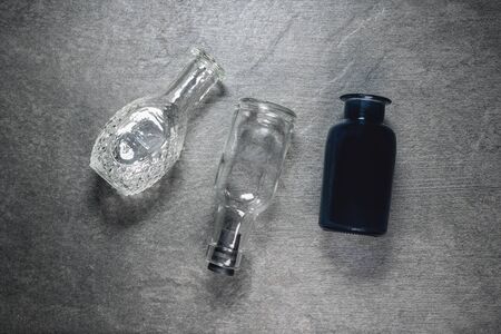 Empty glass bottles on gray flat lay background.