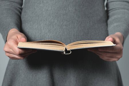 Woman reading open book in her hands close up.の写真素材