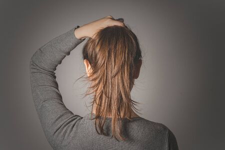 Woman holding bunch of hair in her hand isolated on gray background.の写真素材