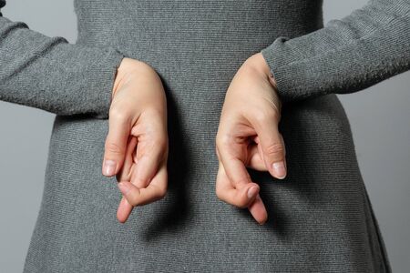 Liar concept. Woman talking untruth and holding her fingers crossed behind her back.の写真素材