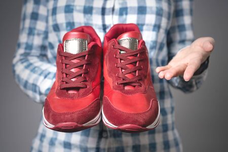 Woman with a pair of new red sport shoes in hands on gray background.の写真素材
