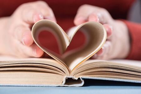 Love read books concept. Woman holding a book pages in heart shape form.の写真素材