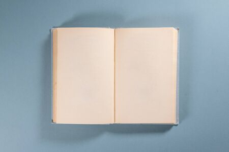 Open blank page book with copy space on blue background.