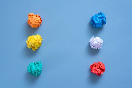 Crumpled colorful paper pages on blue background.