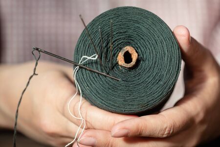 Sewing thread spool and needle in tailor hand close up.の写真素材