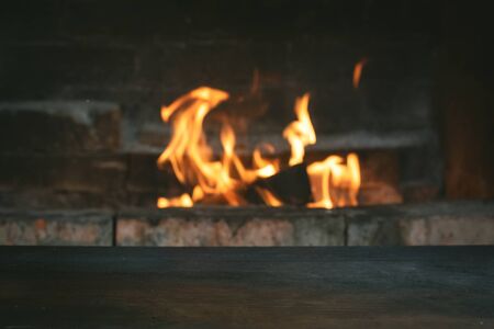 Empty table surface on a burning fire in fireplace background with copy space.の写真素材