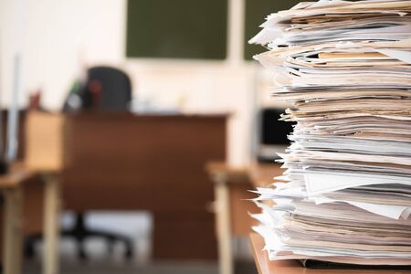 Stack of educational materials on school desk in the classroom abstract background.
