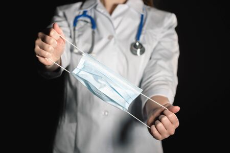 Medical mask in doctor hands close up on dark background.の写真素材