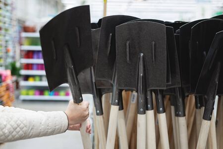 Gardener is buying a new spade in a garden store.