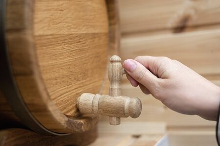 Hand opens a tap of beer barrel close up background.