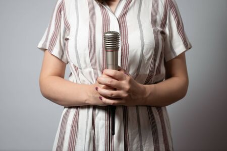 A wireless microphone in a woman hands on a gray background.の写真素材