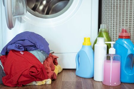 Washing machine, laundry detergent bottles and a dirty clothes in a basket.の写真素材