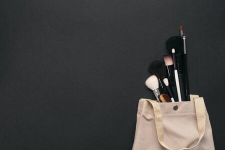 Cosmetic bag and a makeup brushes on a black background with copy space.