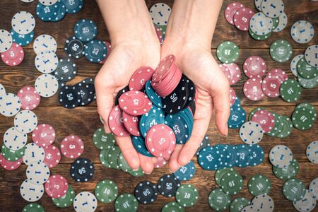 Heap of poker chips in female hands abstract background.