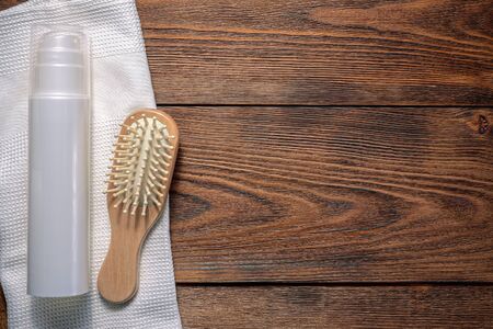Hair balm, towel and hair brush on brown wooden flat lay background with copy space.の写真素材