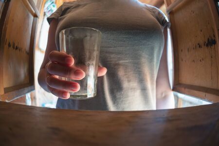 Woman holding in hand an empty drinking glass close up.