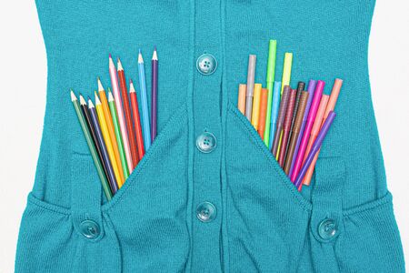 Colorful pencils in a blue sweater pocket flat lay background.の写真素材