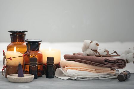 Aromatherapy oil bottles, towel and burning candles on a wooden table. Spa concept background.の写真素材