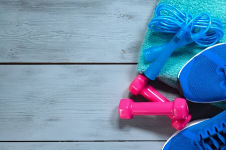Sneakers, dumbbells, jumping rope and a towel on a blue floor. Sport background.の写真素材