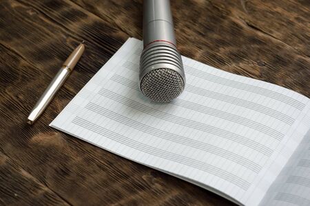 Music book, quill pen and a microphone on the wooden table.の写真素材