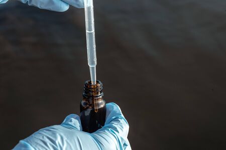 Water pollution concept. Woman scientist takes a water sample from polluted pond.の写真素材