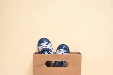 Shopping bag and baby boots on an orange background.