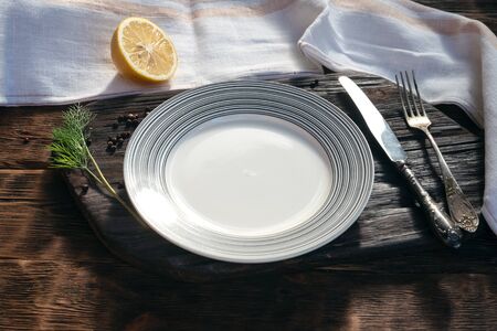 Empty plate with copy space for food on cutting board on a aged wooden kicthen table background.