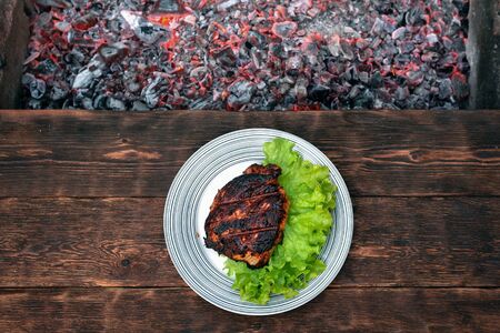 Grilled turkey meat on a plate with a lettuce leaves on a wooden table background with a burning...