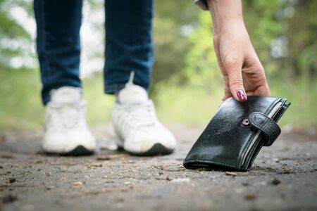 Woman is found a wallet on a ground and picking up it.