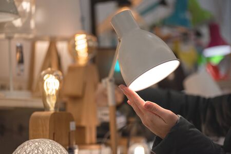 Woman choosing a new desk lamp in a store.の写真素材