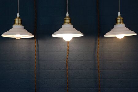 Turned on hanging lamp on a dark wall background.