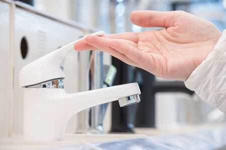 Woman is open faucet. Customer choosing a new faucet and sink for bathroom in the shop.