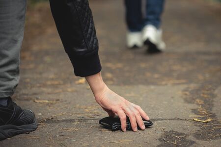 Wallet dropped from a pocket and a male hand picking up it from a ground.の写真素材