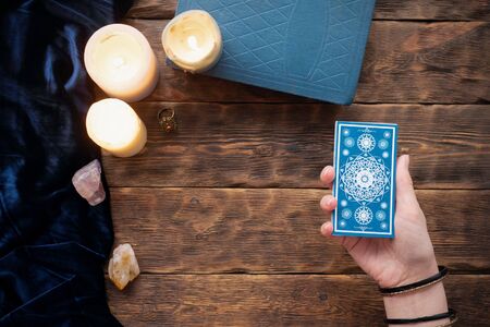 Fortune teller with tarot cards in the hand on brown table background.の写真素材
