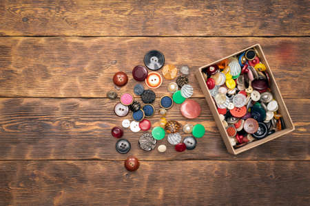 Heap of colorful retro buttons on the wooden flat lay table background with copy space.