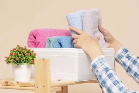Woman is placing a bath towels in a storage box close up.の写真素材
