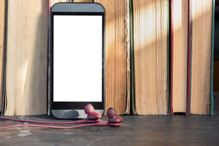 Mobile phone with blank screen with copy space and old books. Electronic book concept.
