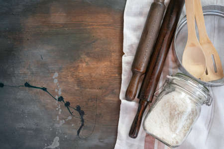Flour in the glass jar, rolling pin, sieve and towel on kitchen flat lay background with copy space.の写真素材