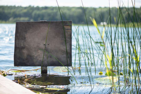 Old wooden plate with copy space for text in the lake water near wooden pier.の写真素材