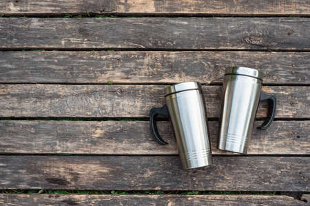 Pair of touristic steel cups on the wooden table background.の写真素材