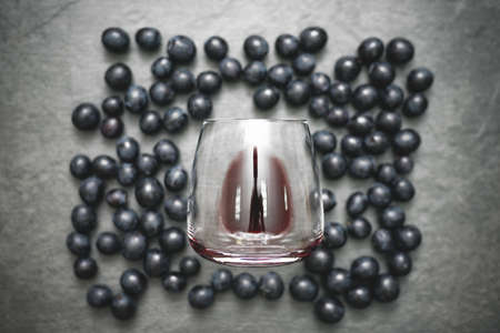 Wine Glass with red wine and black grapes on stone table surface flat lay background.の写真素材