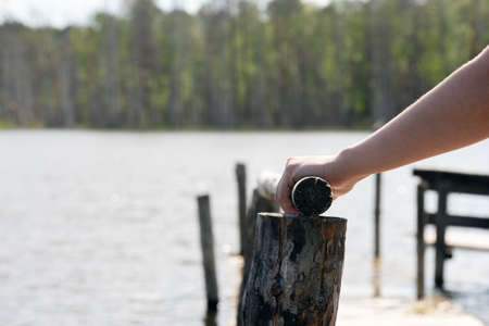 Female hands on the railing of the old pier on pond water background.の写真素材