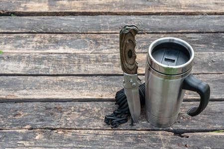 Stainless cup, knife and rope on the wooden table background with copy space.の写真素材