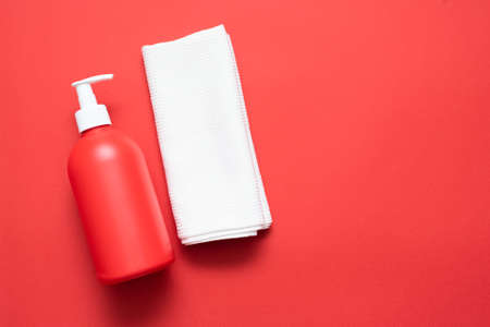 Red liquid soap bottle and white towel on the red flat lay background.の写真素材