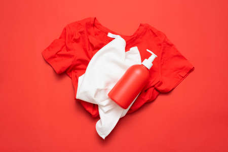 A red tee shirt, white towel and detergent bottle on red flat lay background.の写真素材