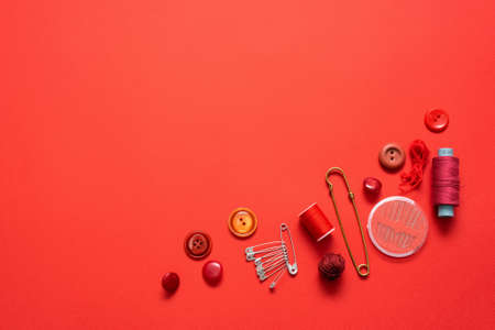 Sewing accessories on the red flat lay background.