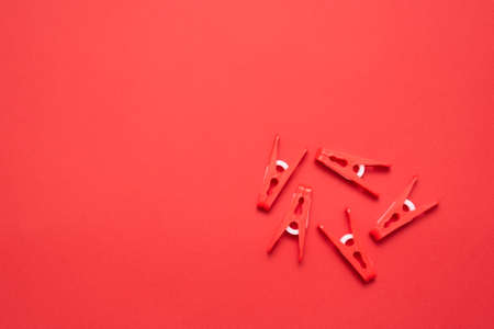 Heap of red clothespins on the red flat lay background.