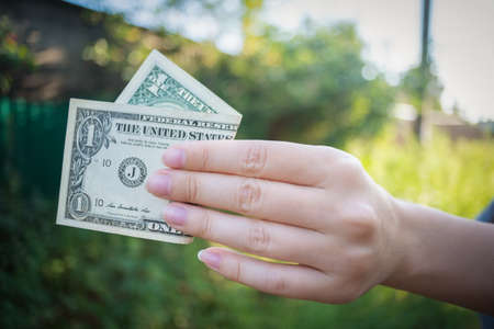 Woman is holding in hands a one dollar close up.の写真素材